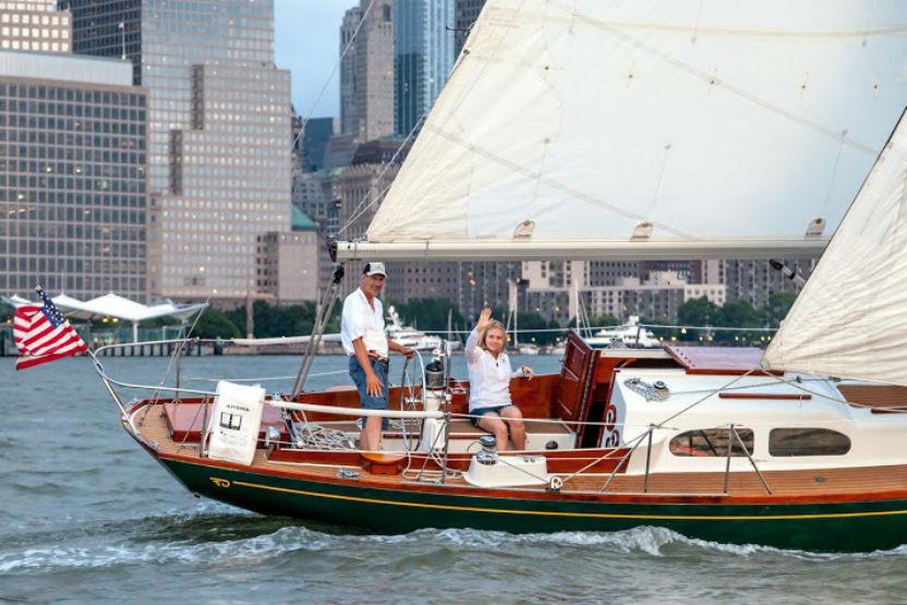 A older women and a man sailing on the NYC waterways with the city skyline in the background