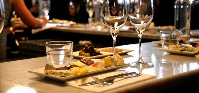 Two wine glasses and a colorful appetizer sit on a bar top at Vanguard Wine Bar in New York City.