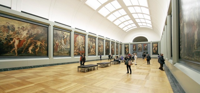 Individuals looking at art lining the walls inside of a museum