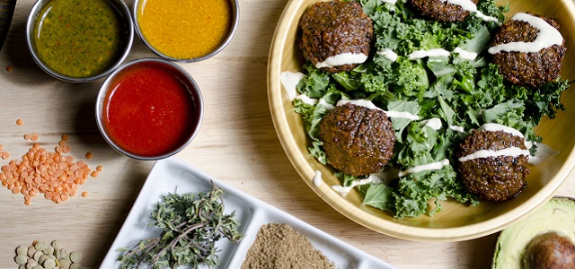 Fresh and colorful picnic food from Maoz Vegetarian on a wooden counter with three bright sauces and crisp green salad.