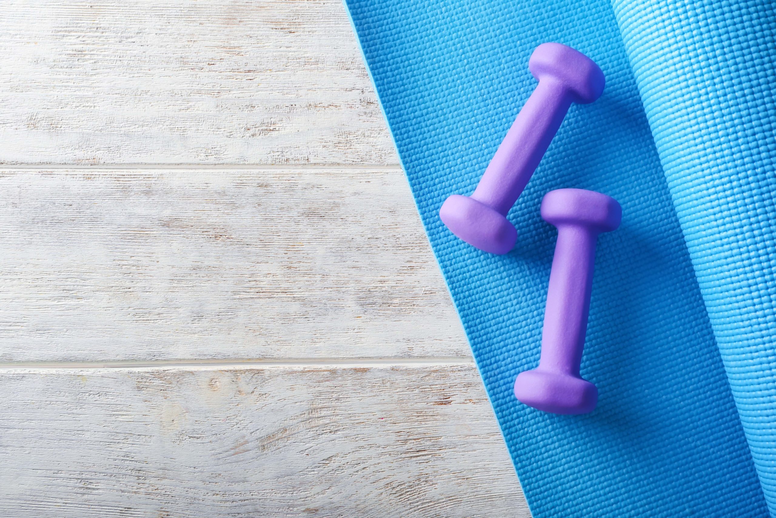 A pair of purple dumbbell weights on a blue exercise mat