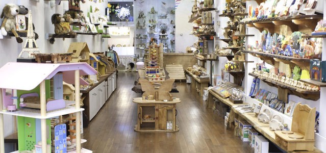 An interior view on toy store Playing Mantis in Tribeca with brown wooden floors and shelves of toys on the walls with bright lights.