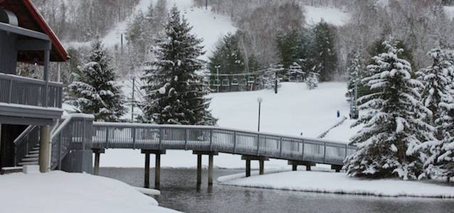 A view of the snow covered mountain and skiing trails at Mohawk Mountain with the lodge and a bridge.