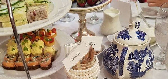 A decorated table with colorful pastries and tea china sitting on a white table cloth at Kings' Carriage House.