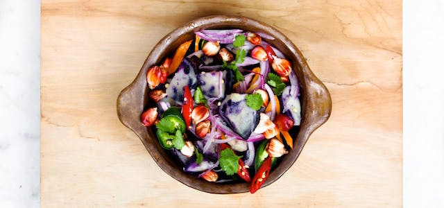 A brown wooden bowl filled with freshly chopped vegetables ready to be put into a crock pot.