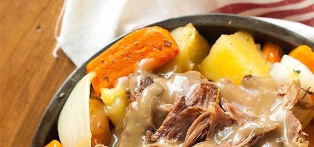 Fresh carrots, potatoes, and meat cooking in a crock pot slow cooker.