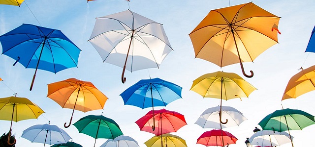 An art image of brightly colored umbrellas in the sky displayed at an art show.