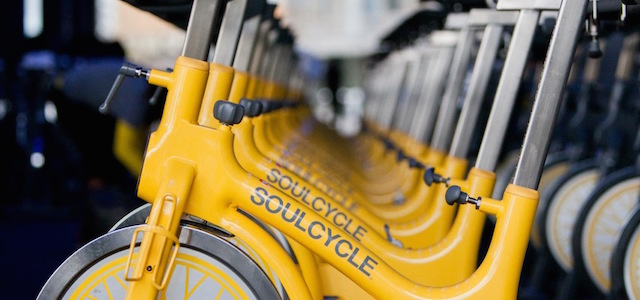 Bright yellow stationary bikes in a spin class room at SoulCycle.