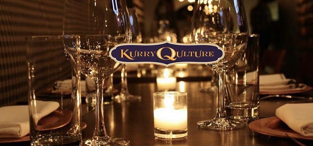 Table view of Kurry Qulture with warm glowing candles and clear wine glasses.