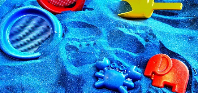 A sandbox with bright blue sand and colorful sand toys.