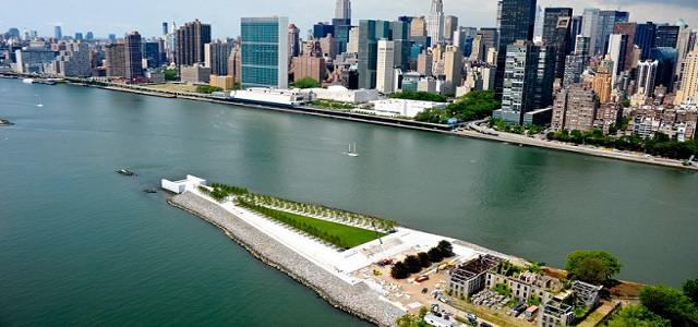 An aerial view of Roosevelt Island in NYC and a green park surrounded by the Hudson Rover.