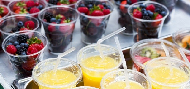 A spread of fresh strawberries, blueberries, and raspberries and orange juice on a table.