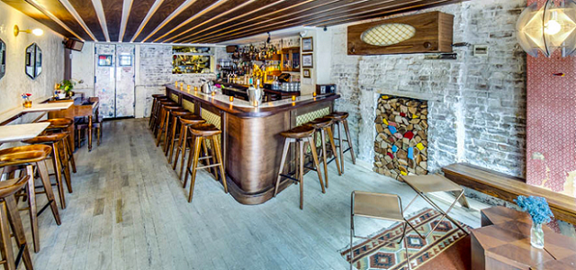 An interior view of Loosie's Kitchen in Brooklyn, NY wooden bar and white washed exposed brick.