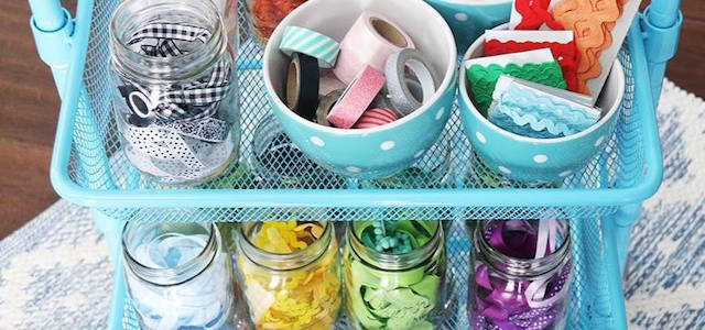 A teal blue crate with shelves of mason jars containing arts and crafts supplies.