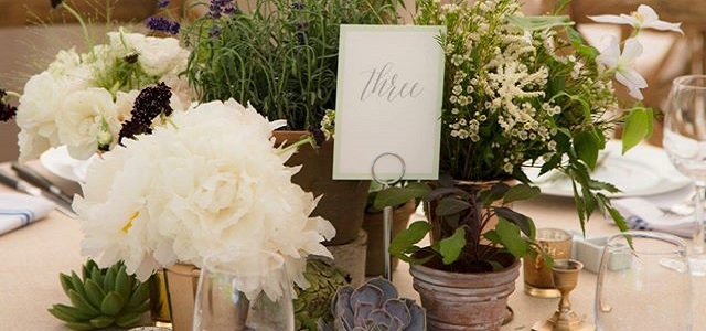 A table with white flowers and greenery for a wedding.