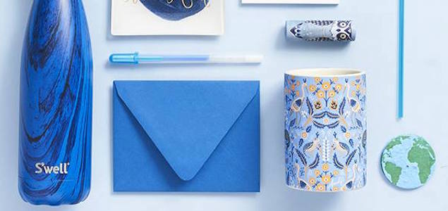 A blue paper envelop, blue S'well water bottle, and a blue paisley coffee mug.