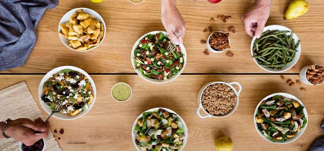 A table top view of fresh green salad and dished of salad toppings at Just Salad in New York City.