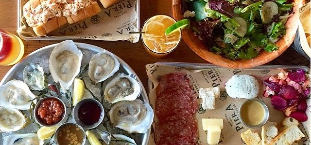 A set of seafood plates and cocktail drinks at Pier A Harbor House in NYC.