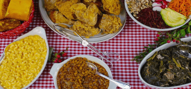 A picnic table top spread of BBQ food dishes.