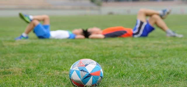 Two boys laying in the grass after playing a game of soccer.