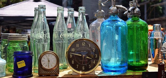 Colorful glass bottles and vases on a table at an outdoor market in New York City.