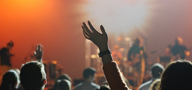 A crowd waving their hands at a night concert.