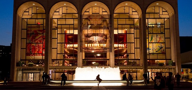 A view of The MET Opera at night with a water fountain. 