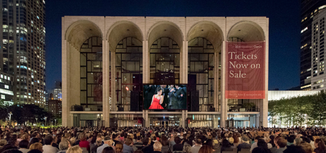 The MET Opera at night with a show playing on a big screen.