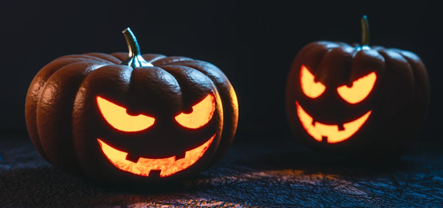 Two carved pumpkins with jack-o-lantern faces lit up at night.