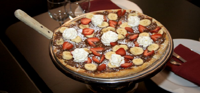 A dessert pizza with fresh strawberries and whipped cream.
