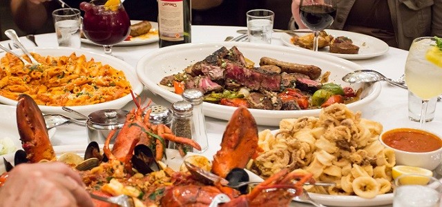 A white linen covered table at Carmine's in New York City with freshly prepared seafood and traditional Italian food options. 