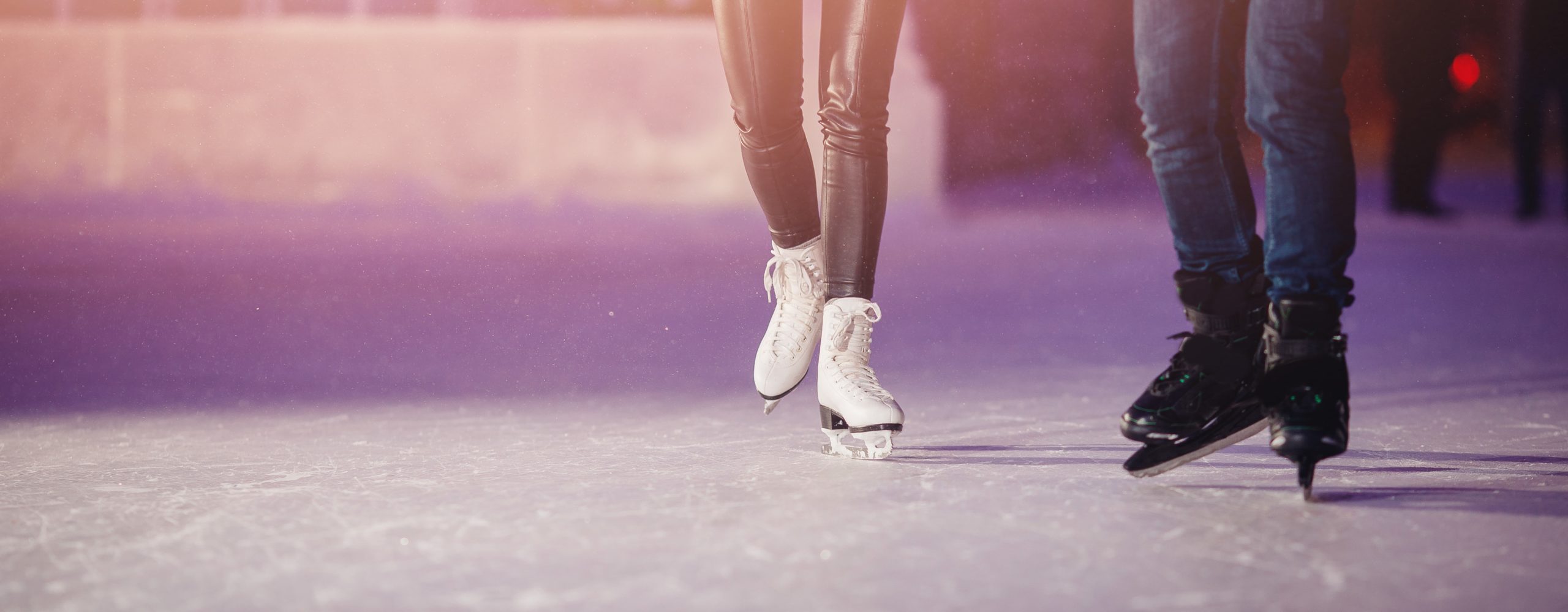 Girl and boy skating on ice on a date, shot of their lower legs on the ice