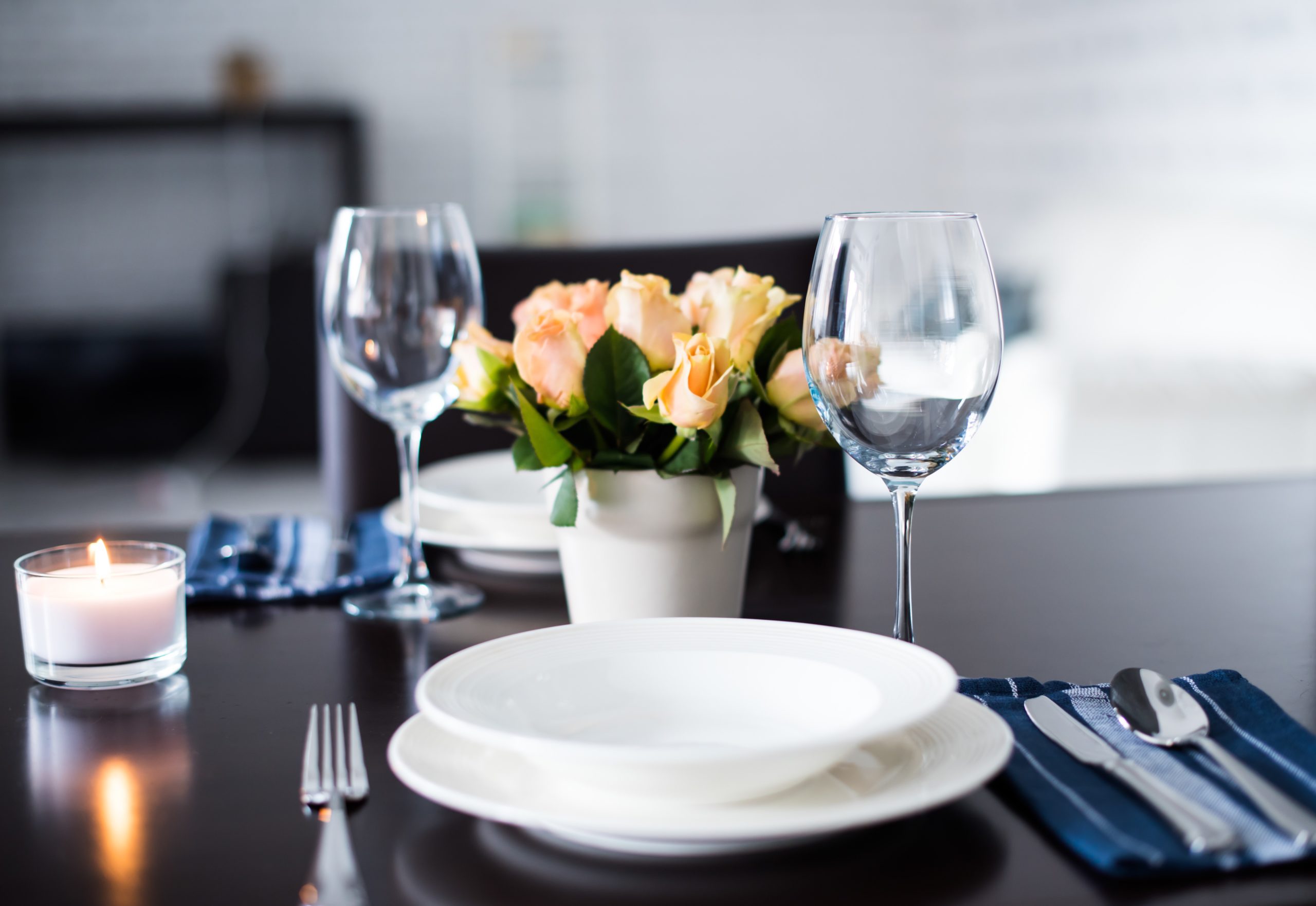 A set dinner table with two wine glasses and yellow roses