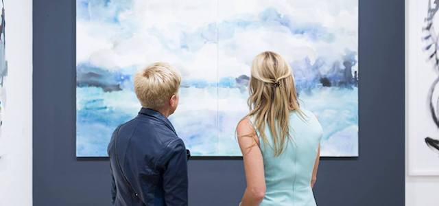 Two women admiring a piece of art with blue coloring.
