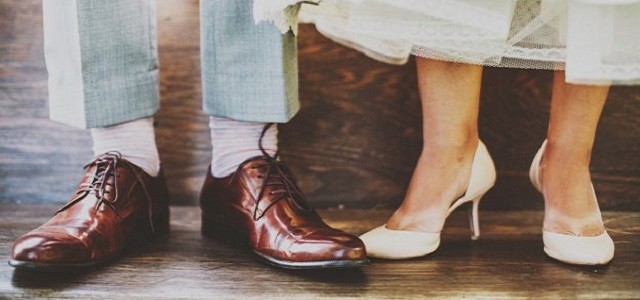 A bride and groom in wedding dress shoes.