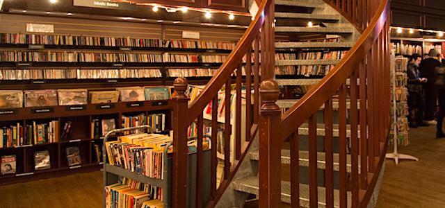 An interior view of a curved wooden staircase with string lights at Housing Works Bookstore in NYC.