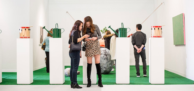 Two women at an indoor art exhibit at The Armory in NYC.