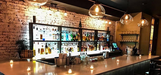 A view of the bar at The Atrium at Hendrik's with exposed brick and dim lighting.