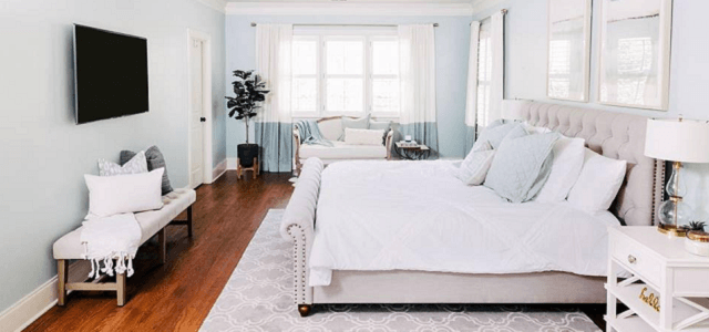 A pastel colored bedroom with white linens.