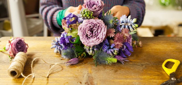 A woman creating a purple and pink flower arrangement.