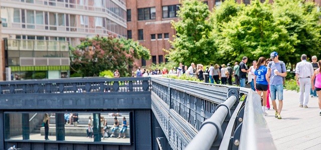 A crowd of people walking outdoors on the Highline in NYC.