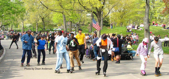 Group of people roller skating through central park