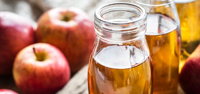 fresh apple cider in mason jar with apples in background