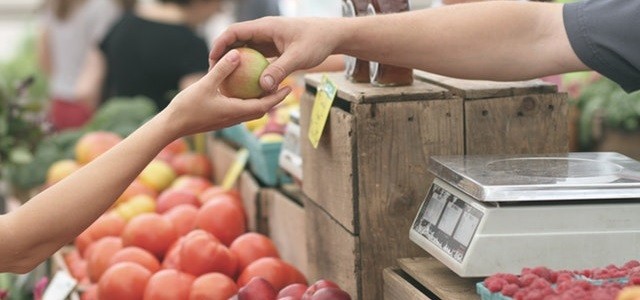 man handing child apple at market