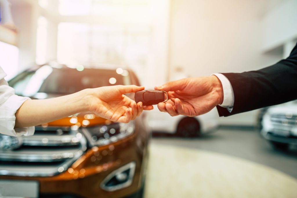 A salesperson handing over car keys to a customer