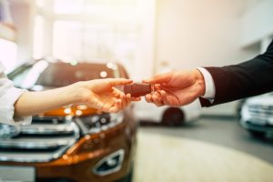 A salesperson handing over car keys to a customer 