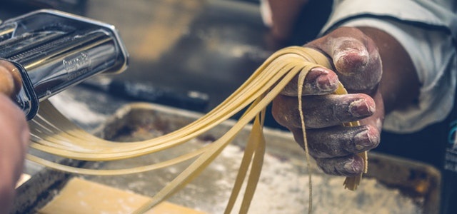 man using machine to create homemade pasta