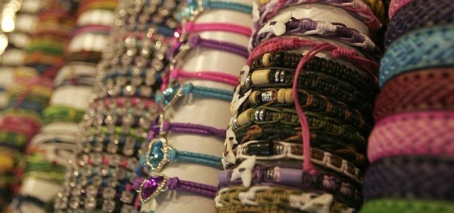 A display of handmade threaded bracelets with colorful beads in a store.