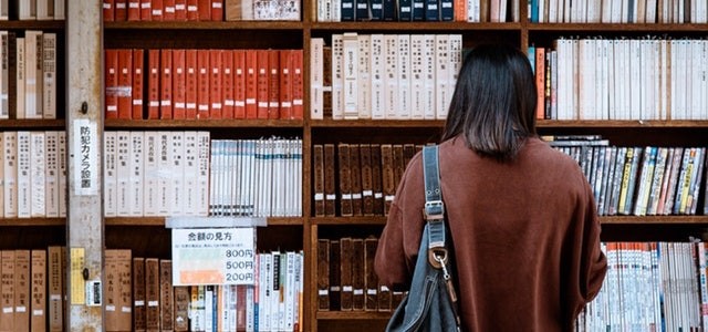 woman searching through shelves at the library