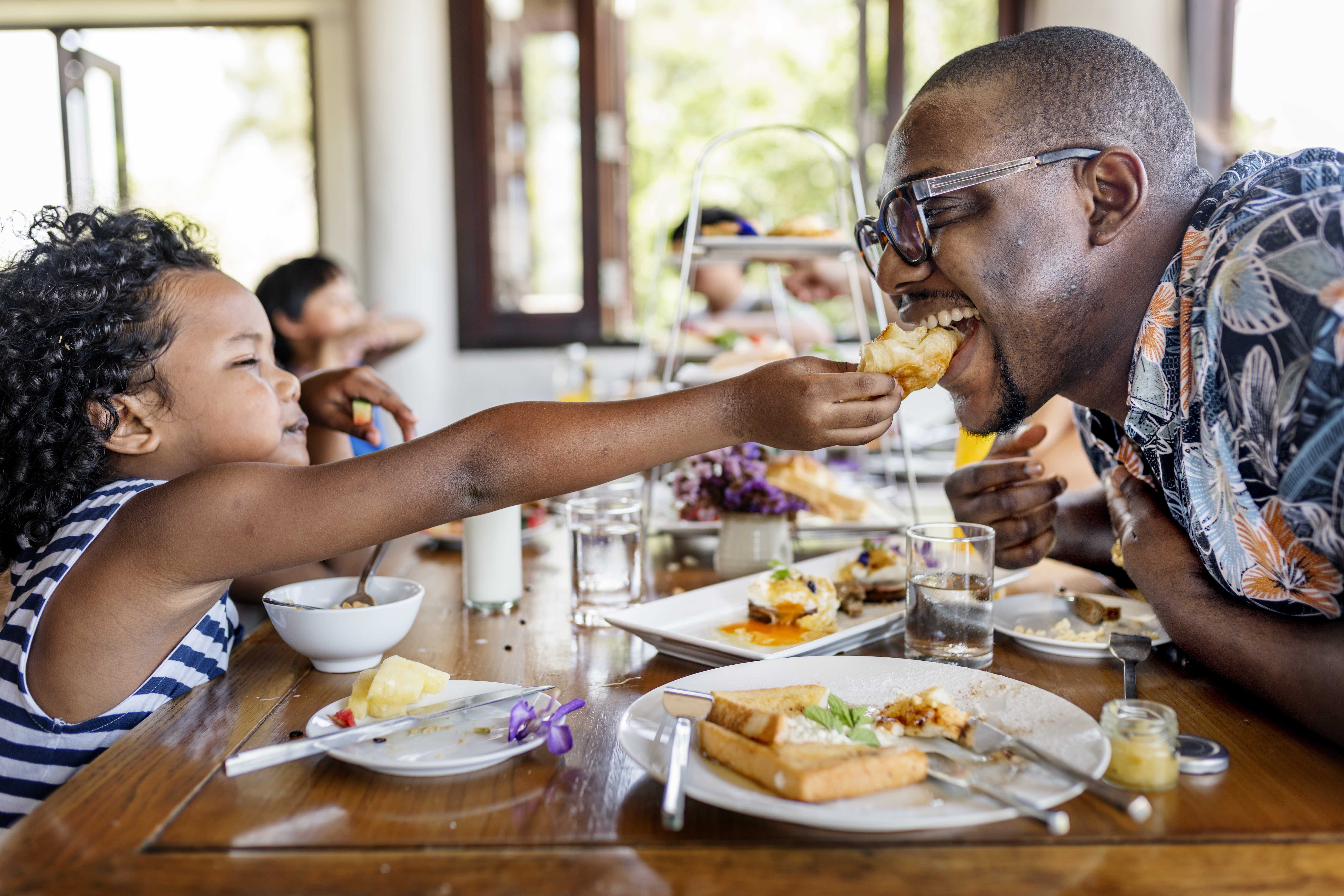 A father and his daughter happy eating in a restauarnt 